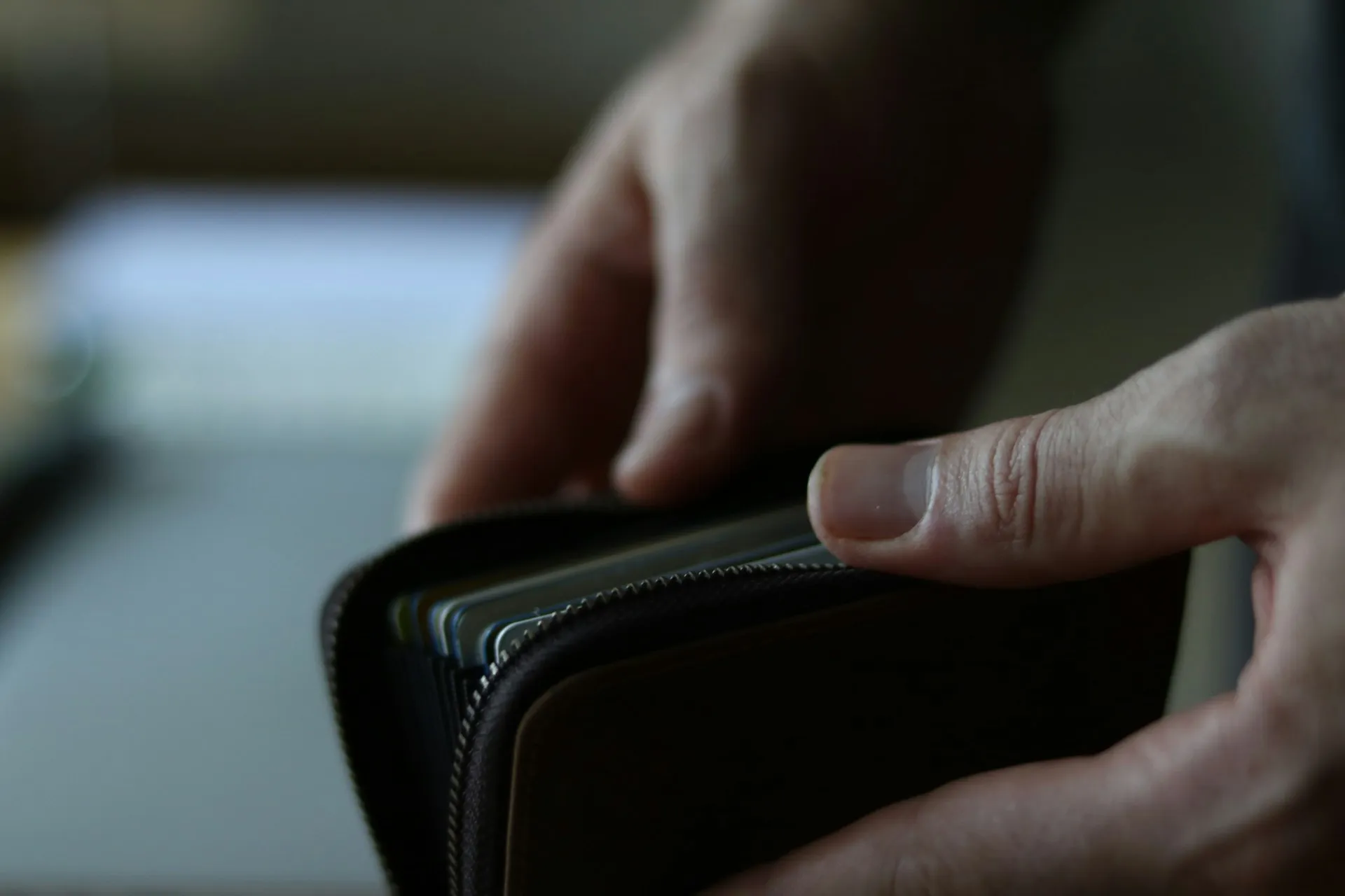 Hände öffnen eine dunkle Geldbörse mit Karten – Symbol für die Frage, ob eine Baufinanzierung ohne Eigenkapital möglich ist