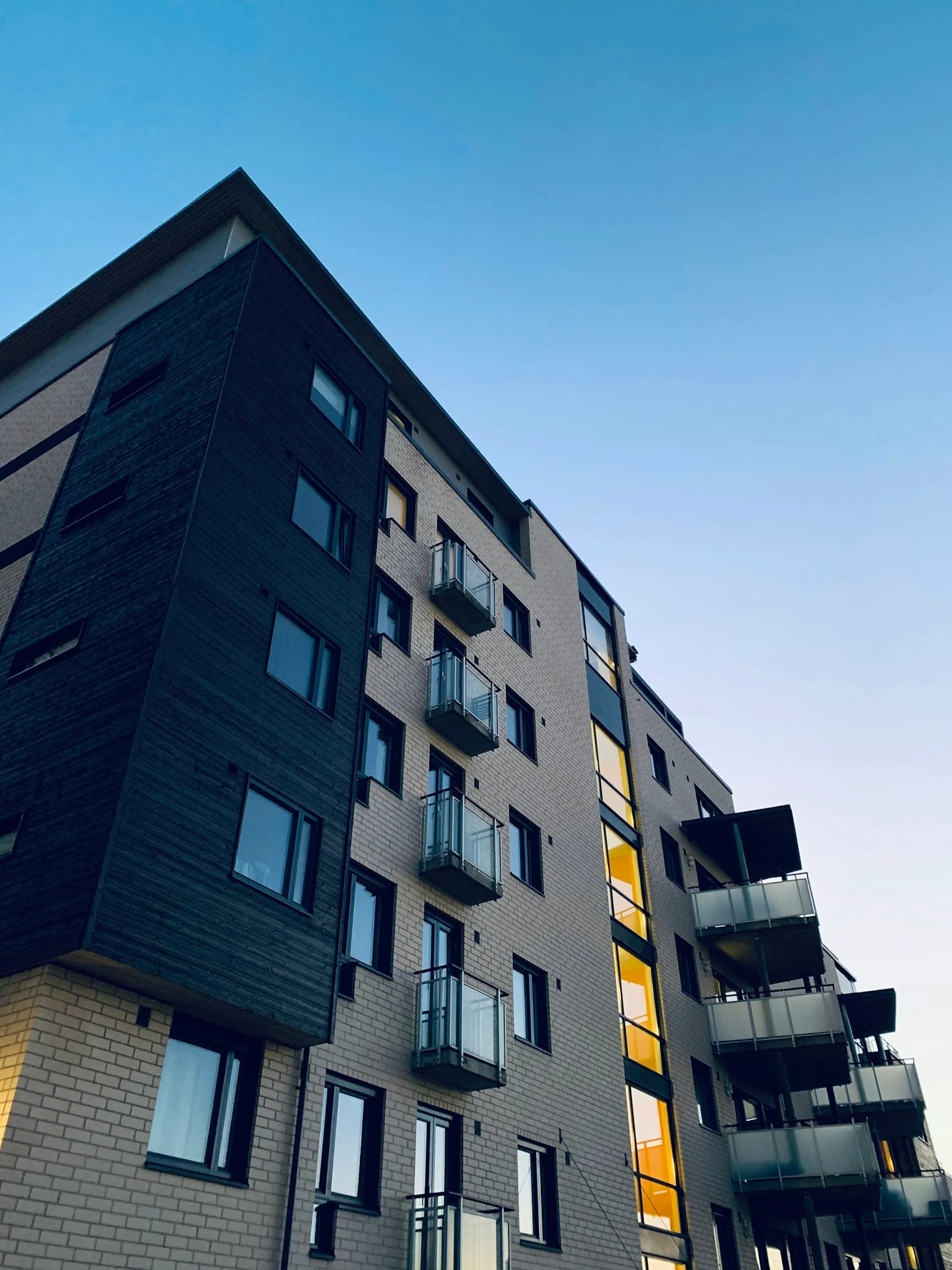 Mehrstöckiges Wohnhaus mit Balkonen vor blauem Himmel – Symbolbild für die Frage: mieten oder kaufen in Dresden