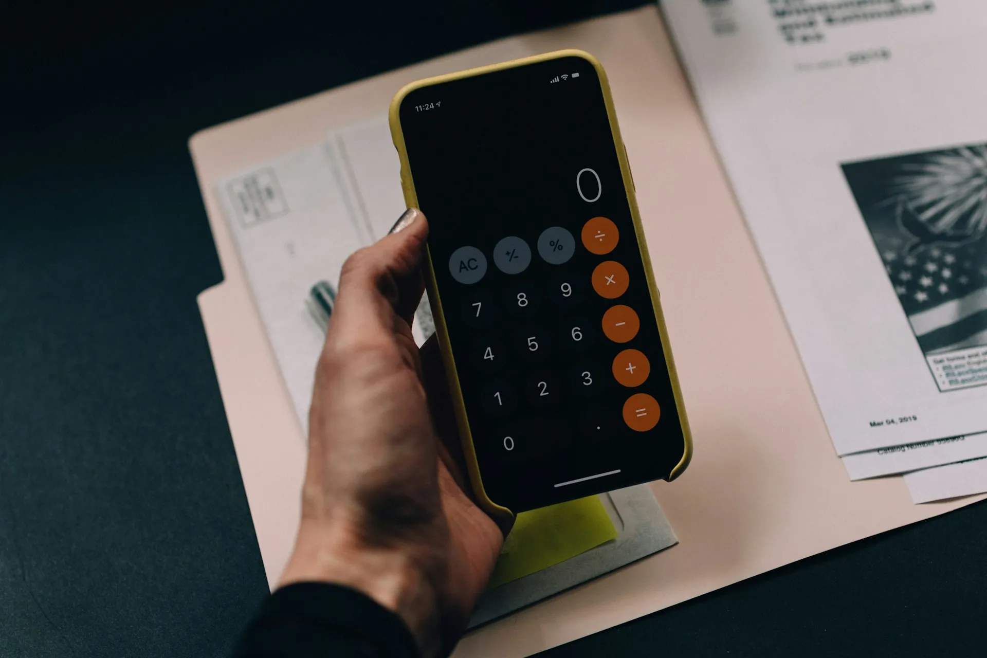 Hand mit Smartphone und Taschenrechner-App über Finanzunterlagen – Tilgung und Rate durchrechnen