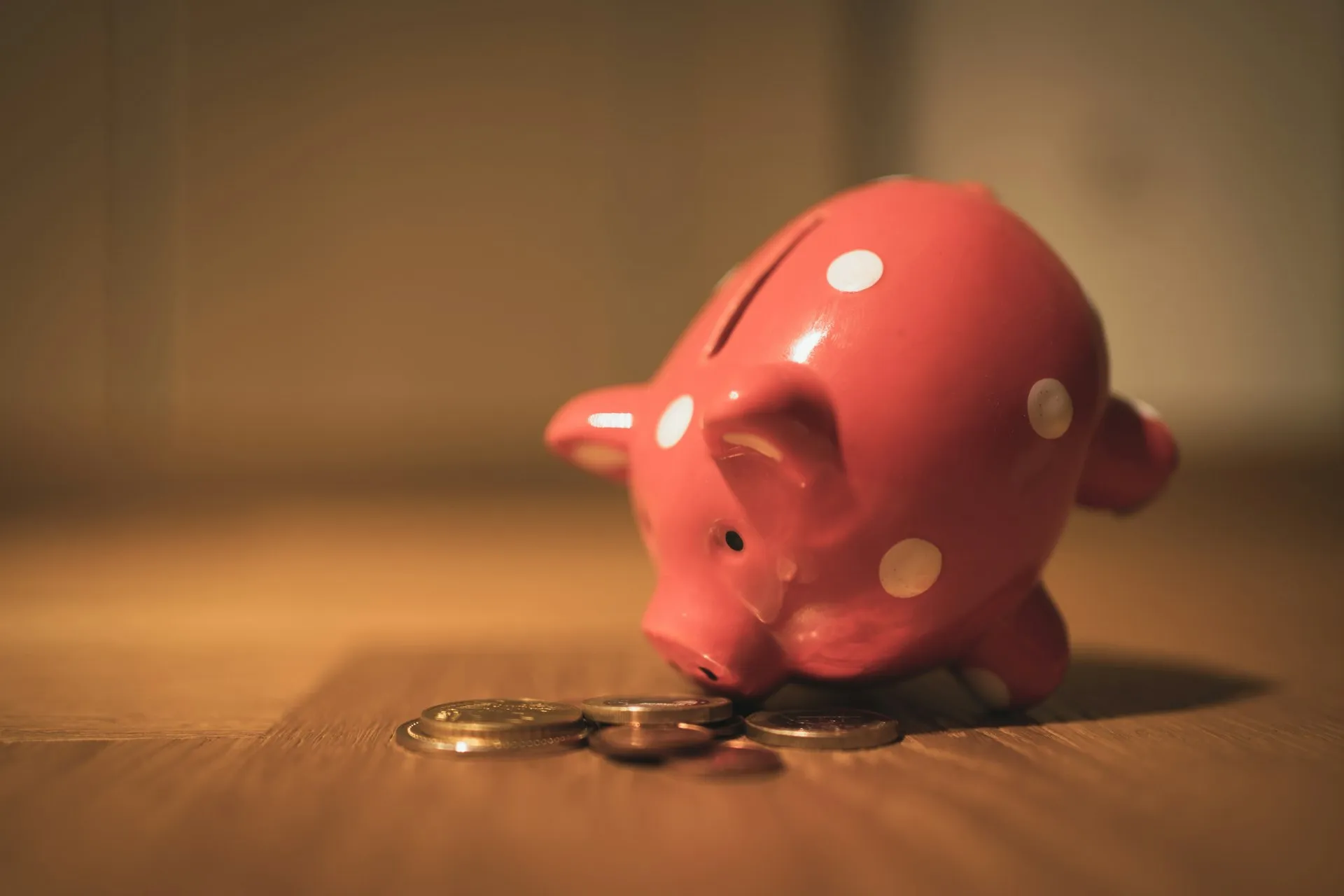 Rosa Sparschwein mit Münzen auf einem Holztisch – Symbol für das Eigenkapital in der Baufinanzierung